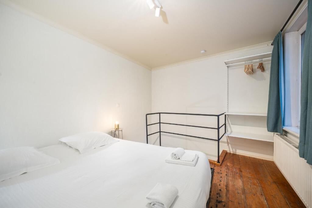 Una habitación con una cama litera, una mesita de noche pequeña con una lámpara y una ventana con cortinas.