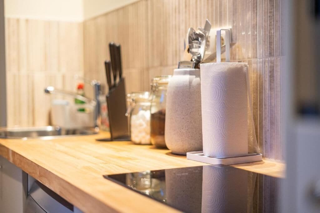 A kitchen counter with a paper towel dispenser, a knife block, and a glass jar.