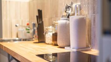 A kitchen counter with a paper towel dispenser, a knife block, and a glass jar.