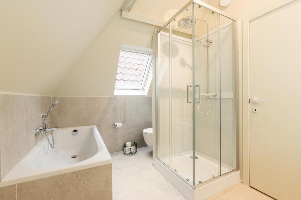 Een moderne badkamer met een glazen douchecabine, een vrijstaand bad en een toilet.