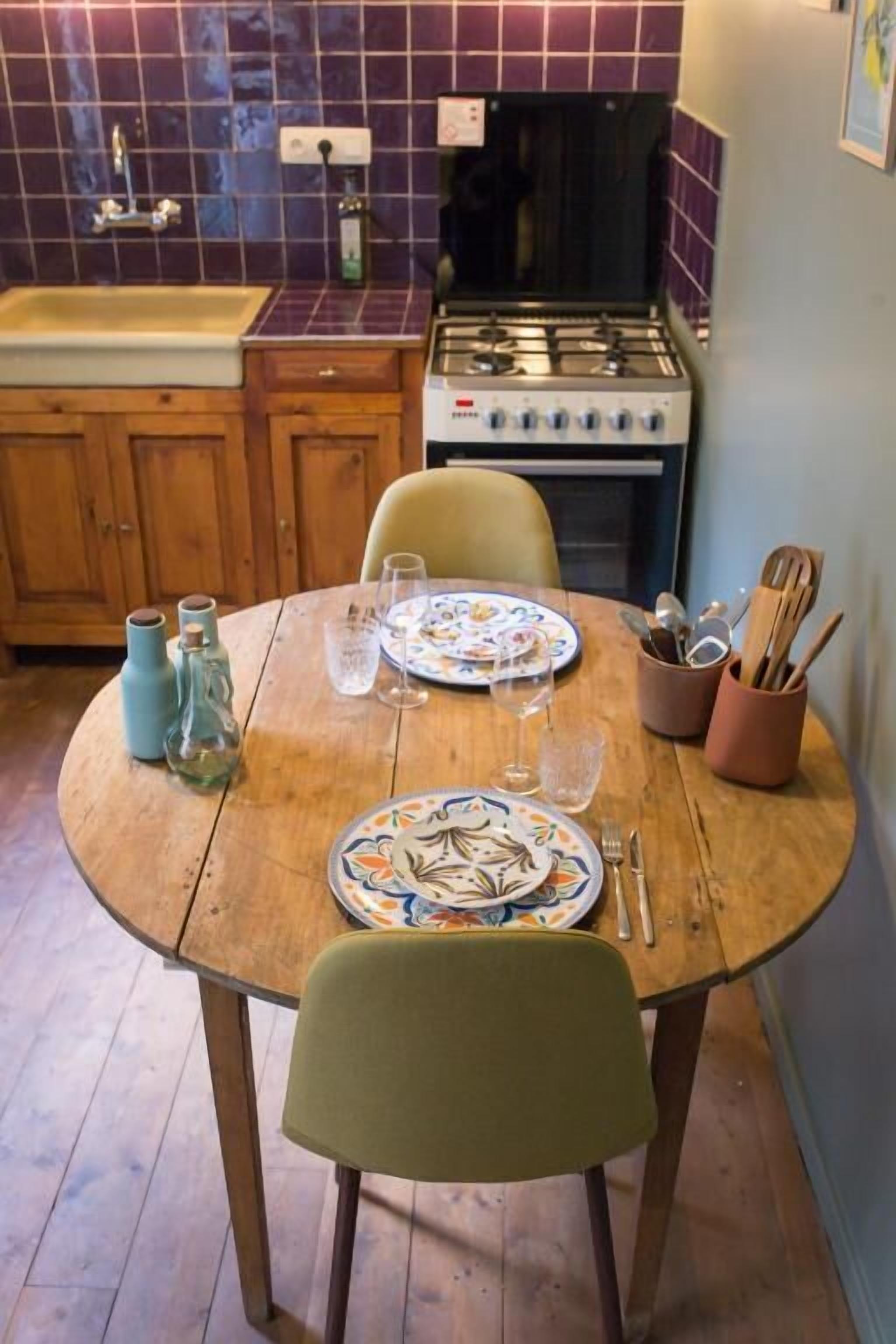 A kitchen with a wooden table set for dining, a stove, and a sink.