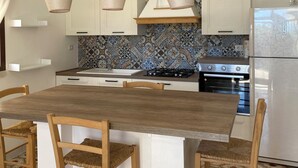 A kitchen with a wooden table, hanging rope lights, and patterned backsplash.