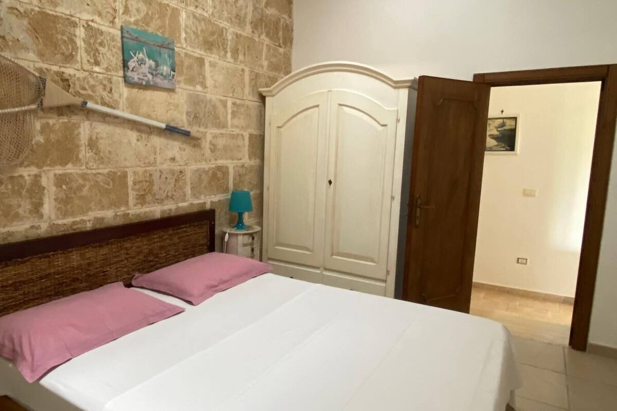 Une chambre à coucher avec un lit, une armoire et un mur en pierre.