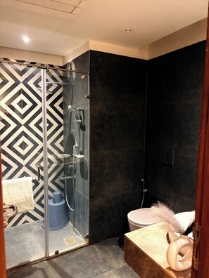 A modern bathroom with a shower, toilet, and a vanity with a towel. - Namaste B&B With Jacuzzi I Noida (Greater Noida)