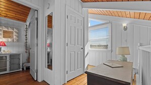 A room with a wooden floor, white walls, a door leading to another room, a window with blinds, and a lamp on a table. - Family Friendly Waterfront Retreat - Dogs Allowed & Off-Season Discounts (Selbyville)