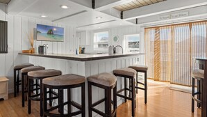 A kitchen with a bar area, wooden stools, a painting, and a sign indicating support for file and release. - Family Friendly Waterfront Retreat - Dogs Allowed & Off-Season Discounts (Selbyville)