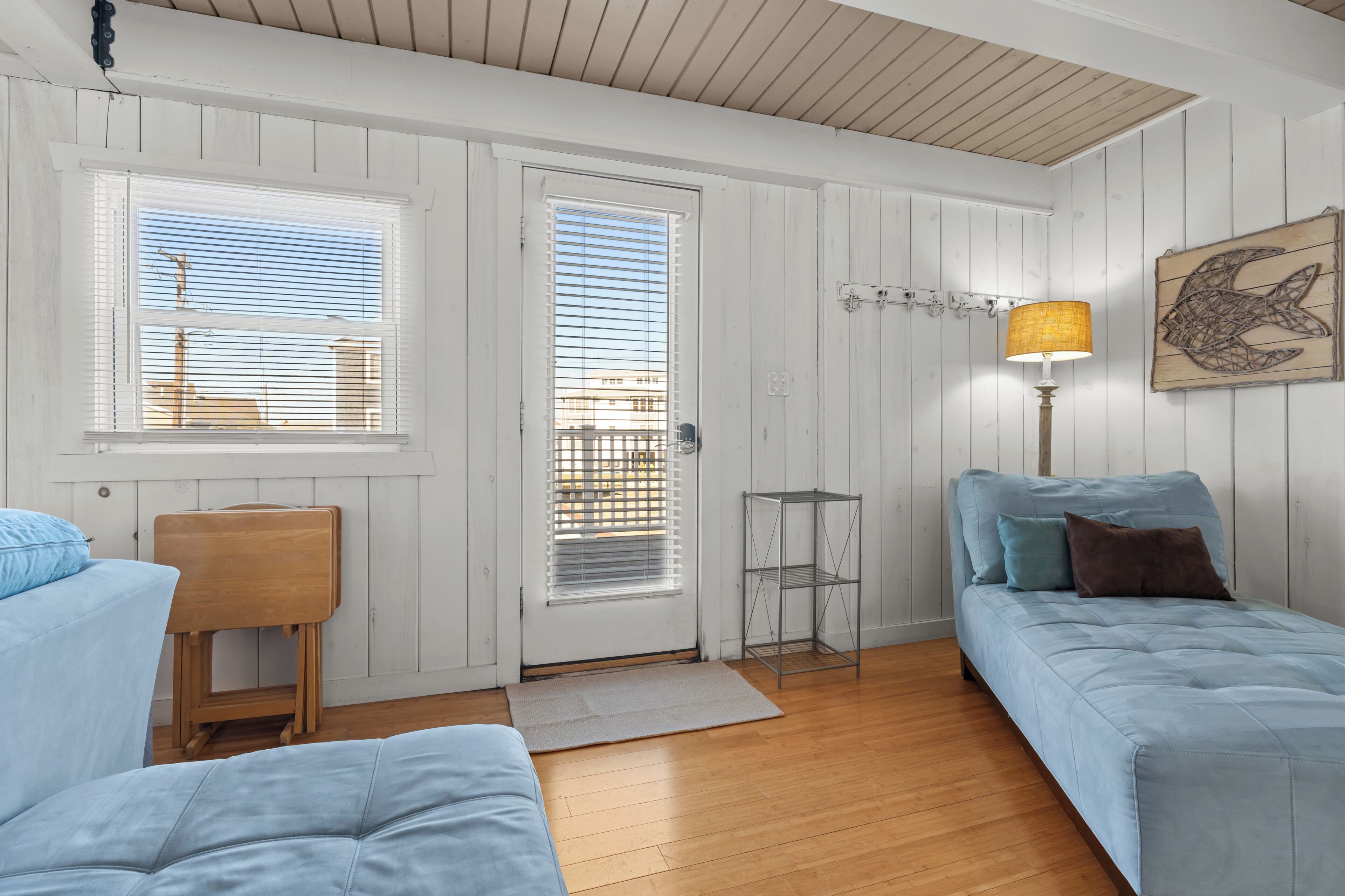 Een kamer met een bed, een stoel, een lamp en een deur voorzien van jaloezieën.
