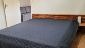 A bedroom with a bed, wooden headboard, and a door leading to another room.
