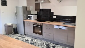 A modern kitchen with a microwave, oven, and dishwasher, a patterned floor, and a trash bin.