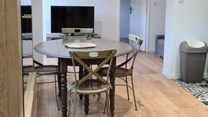 A dining area with a round table, four chairs, a television, and a door in the background.