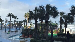 Ein Poolbereich eines Resorts mit Palmen, Liegestühlen und einem Pool.