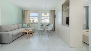 En moderne stue med sofa, et lille bord, spisebord med stole og et fjernsyn.