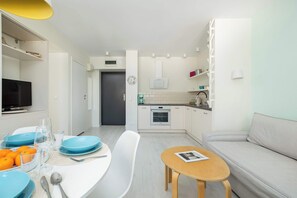 Eine moderne Küche mit weißen Schränken, einem eingebauten Backofen und einem Essbereich mit einem weißen Tisch und Stühlen.
