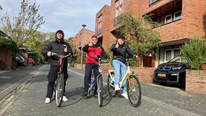 Three people on bicycles in a residential area with brick houses and a parked car. - Charming Rooms with free parking (Amsterdam)