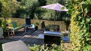 An outdoor deck with a grill, patio furniture, and a view of a river. - Charming Rooms with free parking (Amsterdam)