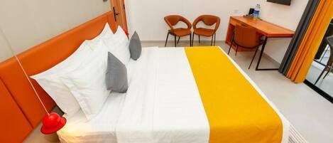 Ein Hotelzimmer mit Bett, Schreibtisch, zwei Stühlen und einem Fernseher an der Wand.
