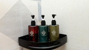 A black soap dispenser shelf with three bottles of shampoo. - Sun Top Grand (Ella)