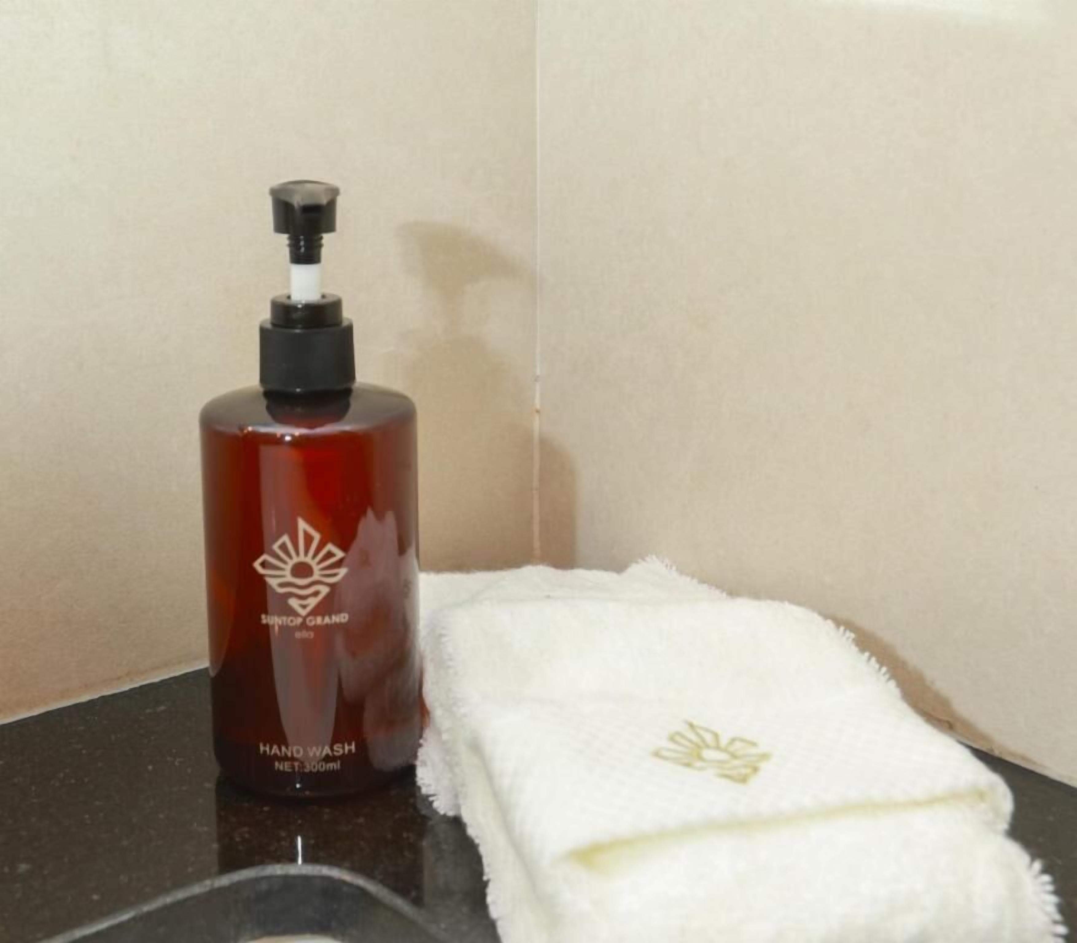 A hand wash bottle and a white towel on a bathroom counter.