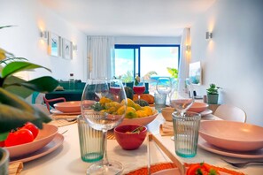 Ein Essbereich mit Tisch für vier Personen, Blick auf das Meer und einem modernen Interieur.