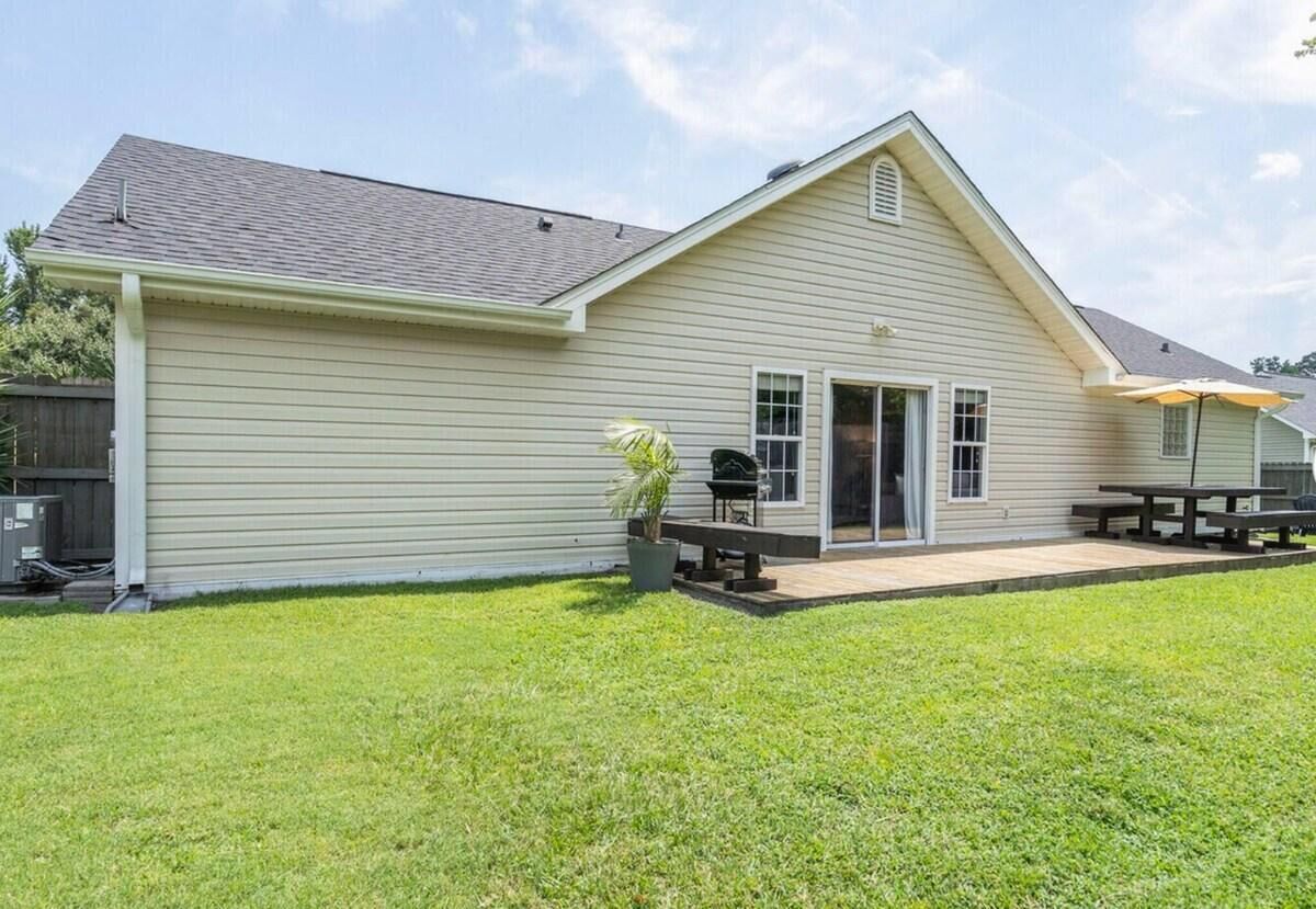 Ein Bungalow mit überdachter Terrasse, Grill und kleinem Garten.