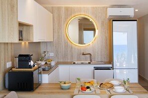 A modern kitchen with a built-in coffee machine, a round mirror, and a view of the sea through a large window. - 1.6 Amapola Moon - beachfront comfort. (Maspalomas)