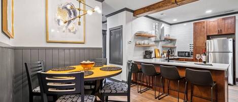Una cocina moderna con una isla central, taburetes de bar y una mesa de comedor con sillas.