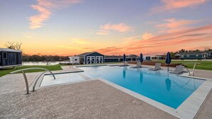 A swimming pool with lounge chairs and umbrellas, a covered area, and a building in the background. - One-of-a-kind tiny home designed for an unforgettable stay by the beautiful San Jacinto River (Highlands)