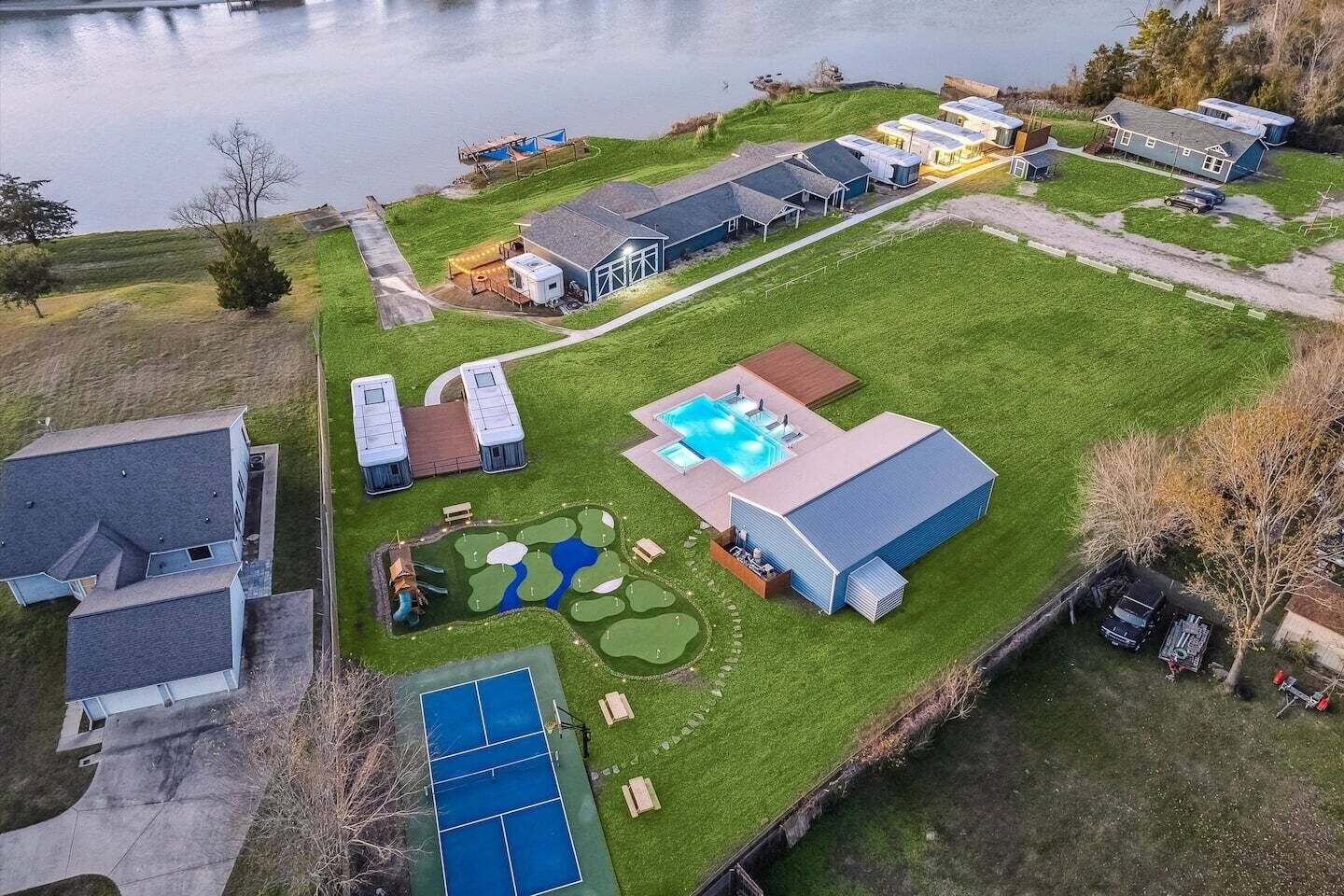 Un quartier résidentiel doté d’une piscine, d’un court de tennis et d’un grand bâtiment comprenant un garage.
