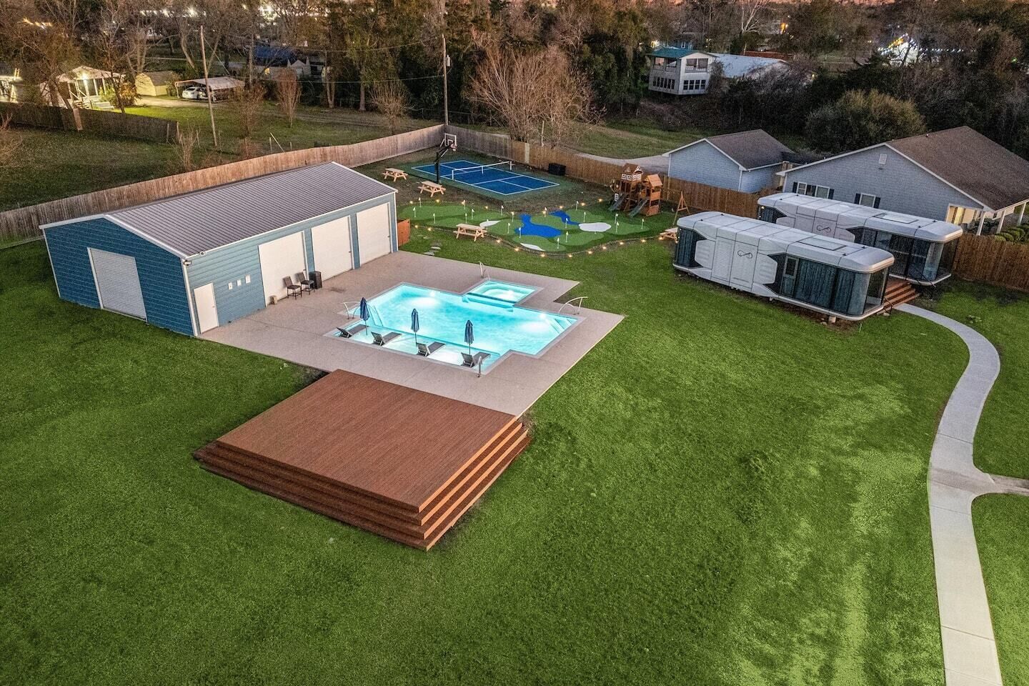 Un jardin avec une piscine, un court de tennis et un espace patio couvert.