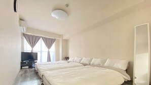 Ett hotellrum med två sängar, en TV, ett skrivbord och ett fönster med gardiner.