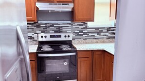 A compact kitchen with wooden cabinets, a built-in oven, and a tiled backsplash. - Lovely 4 Bedrooms Family home, 20 minutes from Downtown. (Baltimore)