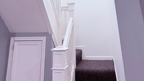 A staircase with white balusters and a dark carpeted landing. - Lovely 4 Bedrooms Family home, 20 minutes from Downtown. (Baltimore)