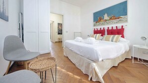 A bedroom with a bed, a chair, a small table, and a painting on the wall. - Albertelli - Large and comfortable apartment for 6 (Roma)
