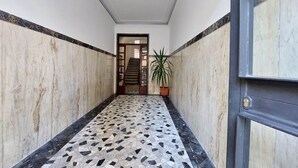 A hallway with a tiled floor, a potted plant, and a door with a lock. - Albertelli - Large and comfortable apartment for 6 (Roma)