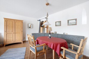 Un coin repas avec une table dressée pour deux personnes, un buffet en bois et un canapé à carreaux.