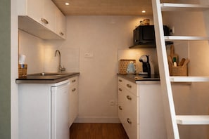 A compact kitchen with white cabinets, a stainless steel sink, a microwave, and a coffee maker. - Studio near the sea and Sables promenade, for 3 guests (Les Sables-d´Olonne)