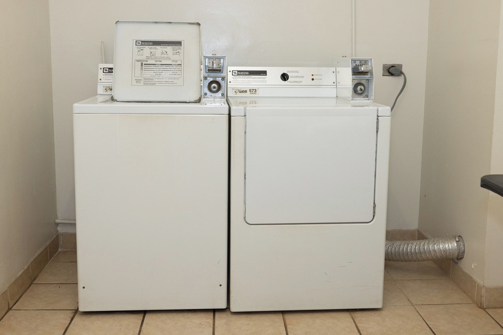 A laundry area with two stacked washers and dryers, a control panel, and a vent.