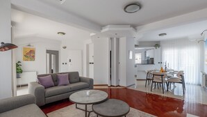 Ein modernes Wohnzimmer mit einer Couch, zwei runden Tischen und einem Essbereich mit Stühlen.