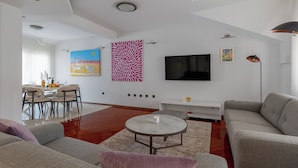 Ein modernes Wohnzimmer mit Essbereich, einem Flachbildfernseher und einem großen Fenster.