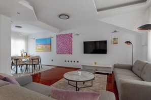 Un salon moderne comprenant un coin repas, un téléviseur à écran plat et une grande fenêtre.