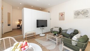 Ein modernes Wohnzimmer mit einem Flachbildfernseher, Korbmöbeln und einer Obstschale.