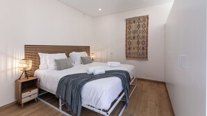Ein modernes Schlafzimmer mit Bett, Nachttisch, Lampe und Wandbehang mit Muster.
