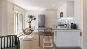 Een moderne keuken met een centraal eiland, een zithoek met rieten stoelen en een bank met gestreepte kussens.