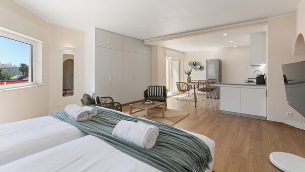 Een moderne hotelkamer met een bed, een eethoekje en een kitchenette.