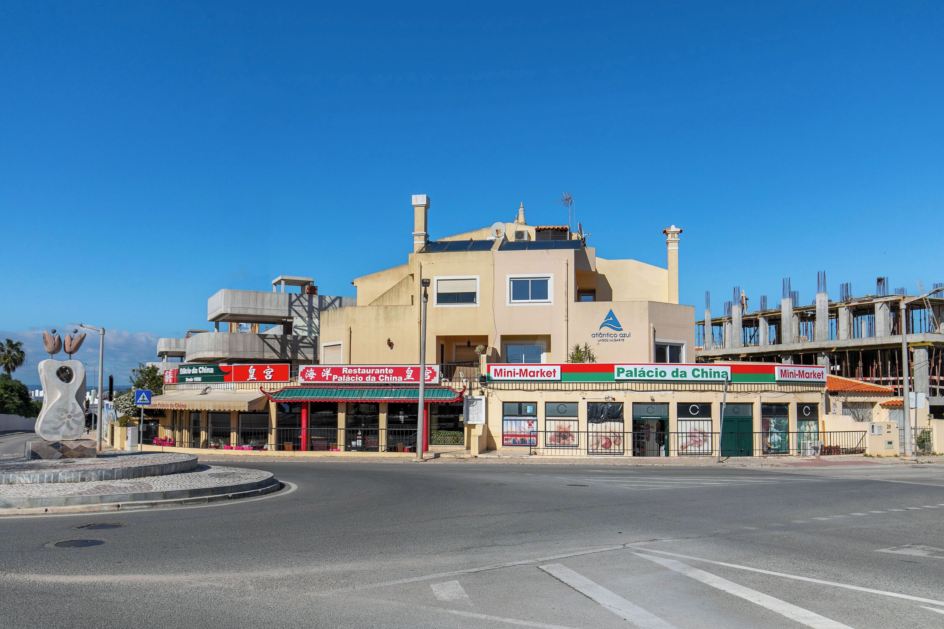 Straßenansicht mit einem Gebäude, das ein Restaurant, einen Markt und ein Schild für 'Palácio da China' zeigt.