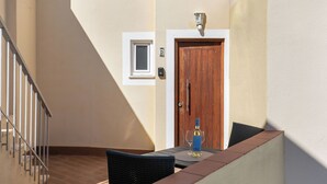 Un balcón con una mesa, sillas, una botella de vino y una puerta.