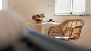 Un comedor con una mesa, una silla de mimbre, un cuenco de fruta y un ventanal.