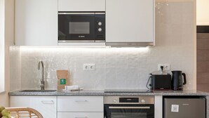 Una cocina equipada con microondas Bosch, cafetera, lavavajillas y refrigerador.