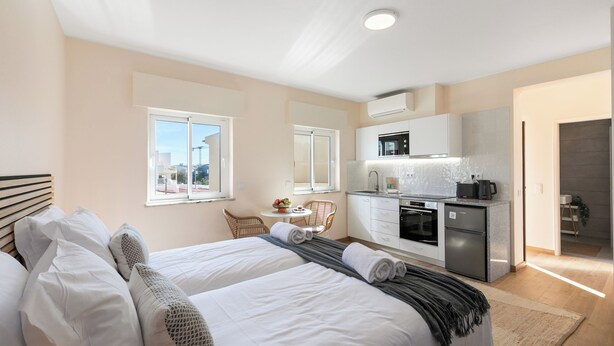 Una habitación de hotel con dos camas, kitchenette, comedor y vistas a la ciudad.