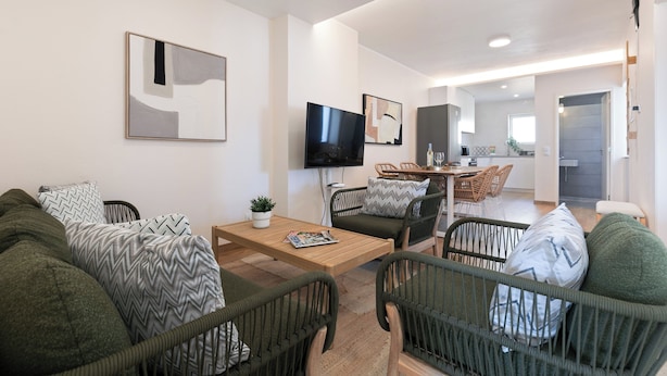 A modern living room with a sofa, chairs, a coffee table, a TV, and a dining area. - Atlântico Azul - Apartment E (Lagos)